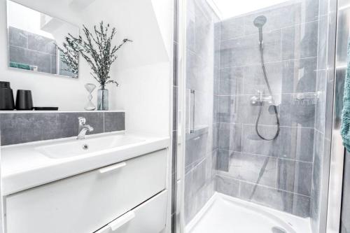 een witte badkamer met een douche en een wastafel bij Le Soft Indus - Duplex avec parking et balcon proche Aéroport Paris CDG in Montfermeil