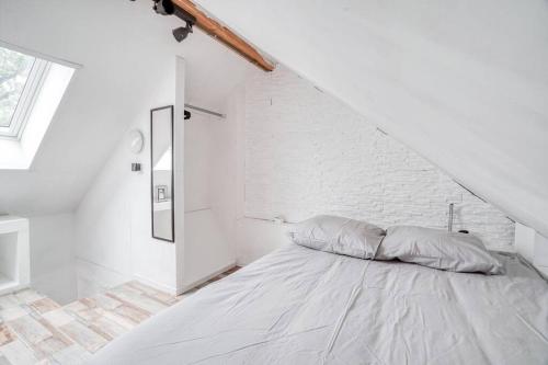 een witte slaapkamer met een bed en een bakstenen muur bij Le Soft Indus - Duplex avec parking et balcon proche Aéroport Paris CDG in Montfermeil