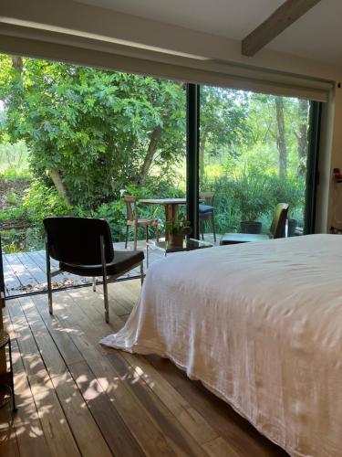 a bedroom with a bed and a large window at BoisBolchet Ecolodge-SPA in Bouillargues