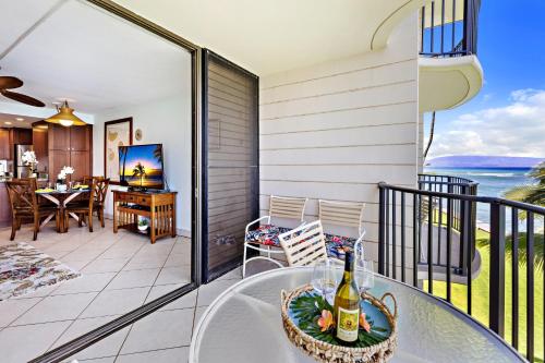 a balcony with a table and a bottle of wine at Kahana Reef 318 in Kahana
