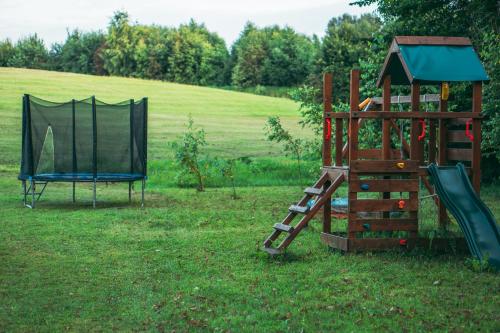 a playground with a slide and a play structure at Šeimos Namelis Adomo Sodyboje prie ežero 35 km nuo Vilniaus šalia Dubingių 