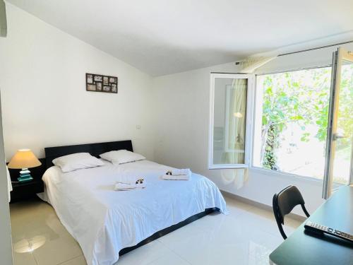 a white bedroom with a bed and a window at Maison de vacances proche du centre de Saint Raphael in Saint-Raphaël