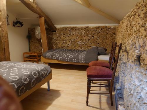 a bedroom with two beds and a stone wall at Domaine Casquil in Panjas