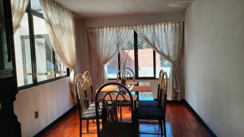 a dining room with a table and chairs and windows at Apartamento acogedor independiente incluye garaje in La Paz