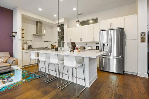 a kitchen with white cabinets and a kitchen island with bar stools at Chic, Modern Silver Lake Oasis with Rooftop Panoramic DTLA Views & Private Garage in Los Angeles
