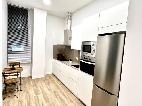 a kitchen with white cabinets and a stainless steel refrigerator at Loft RioArga. Comodidad y Estiloa a 5 min Centro. Nuevo!!! in Pamplona
