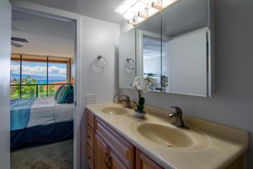 a bathroom with two sinks and a mirror and a bed at Kahana Villa E409 in Kahana