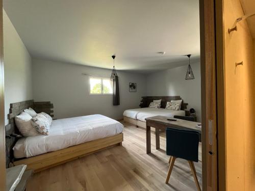 a bedroom with two beds and a table and a couch at Hôtel En Tilleul in Pont-du-Navoy