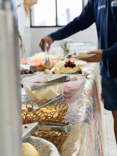 a buffet line with food and a person preparing food at Central Hotel in Campina Grande