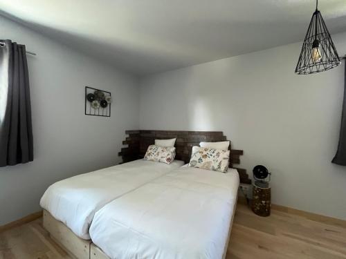 a bedroom with a white bed with two pillows at Hôtel En Tilleul in Pont-du-Navoy