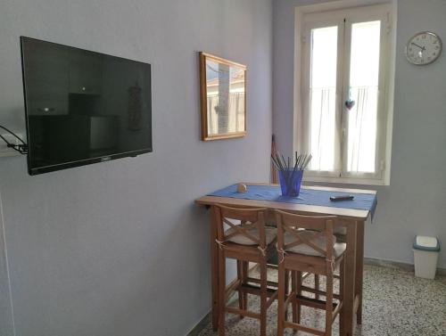 uma mesa com duas cadeiras e uma televisão na parede em Bilocale per vacanze a Vada em Vada