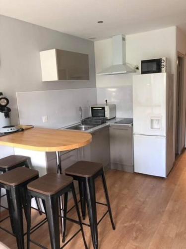 une cuisine avec une table et des chaises en bois et un réfrigérateur dans l'établissement Appartement rénové RDC terrasse 200m plage, à Port-la-Nouvelle