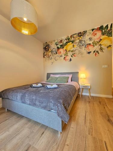 a bedroom with a bed with flowers on the wall at Pachnące Sny Apartament in Elblag