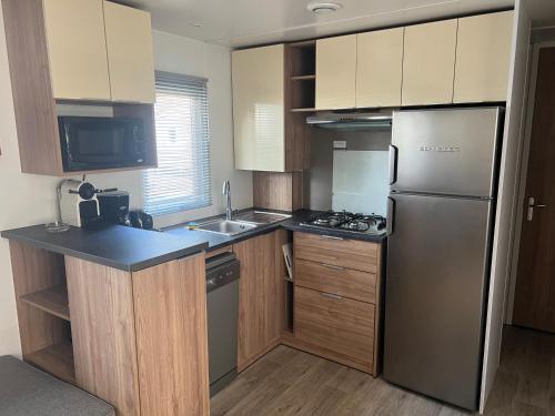 une petite cuisine avec un réfrigérateur et un évier dans l'établissement MOBILHOME CAMPING 4 étoiles NARBONNE-PLAGE, à Narbonne