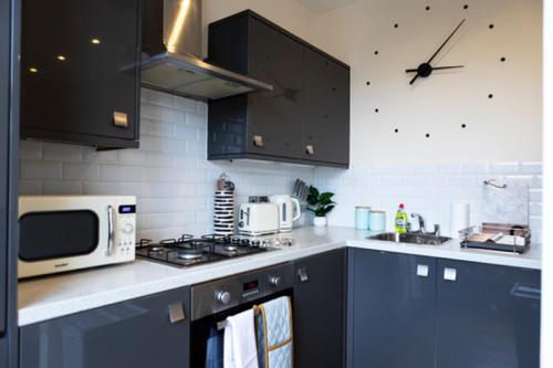 a kitchen with dark blue cabinets and a microwave at 94b Mackenzie road in London