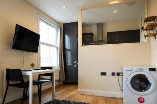 a living room with a table and a washing machine at 94b Mackenzie road in London