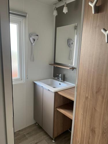 une salle de bain avec un lavabo, un miroir et une fenêtre dans l'établissement MOBILHOME CAMPING 4 étoiles NARBONNE-PLAGE, à Narbonne