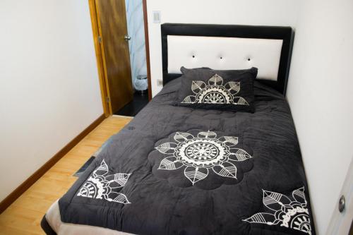 a bed with a black and white comforter and pillows at Hostal Lucas Corferias - Habitaciones Privadas in Bogotá