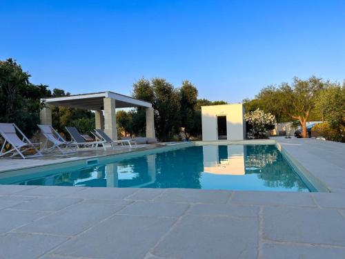 a swimming pool with chairs and a gazebo at Villaria Luxury apulian villa with pool in Campomarino