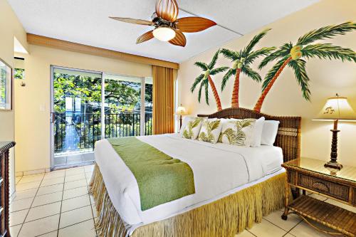 a bedroom with a bed with palm trees on it at Hololani A203 in Kahana