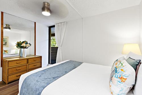 a bedroom with a bed and a dresser and a mirror at Paki Maui 319 in Kahana