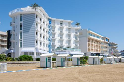 a hotel on the beach with umbrellas in front of it at Hotel Montecarlo in Caorle