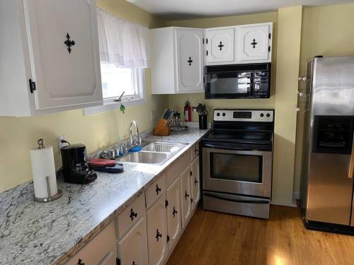 a kitchen with white cabinets and stainless steel appliances at Sunny One Bedroom in Historic Downtown Dover in Dover