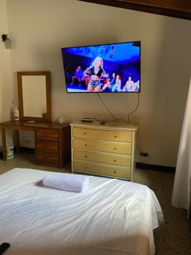 1 dormitorio con 1 cama y TV en la pared en CASA FAMILIAR AMPLIA MUY FRESCA en Medellín