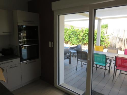 une cuisine avec une porte coulissante en verre menant à une terrasse dans l'établissement 12 pers, sur la dune, PMR, spa, hammam, salle de sport, à Barbâtre