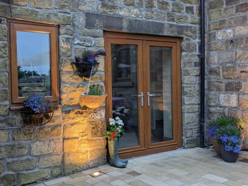 a brick building with a wooden door and flowers in a vase at Charming 1-Bed Cottage on the outskirts of Haworth in Keighley