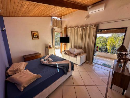 ein Schlafzimmer mit einem Bett, einem Sofa und einem Fenster in der Unterkunft Pousada Vale das Primaveras in Três Corações