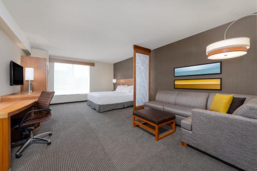 a hotel room with a couch and a bed and a desk at Hyatt Place San Jose Airport in San Jose