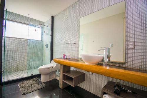 a bathroom with a sink and a toilet and a mirror at Playa Centro Rooftop Apartments & Studios in Playa del Carmen