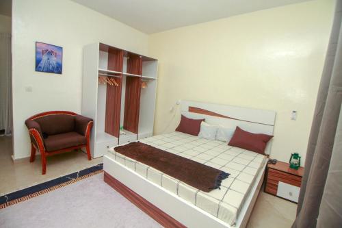ein Schlafzimmer mit einem Bett und einem Stuhl in der Unterkunft "La Coquille", joli loft, moderne, propre, sûr et calme au cœur de Saly in Saly Portudal