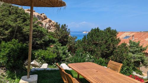 einen Holztisch und Stühle mit Meerblick in der Unterkunft Residence Cala Francese - Case sul mare in La Maddalena