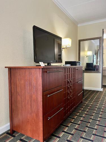 a television on top of a wooden dresser in a hotel room at West Bank Inn in Augusta