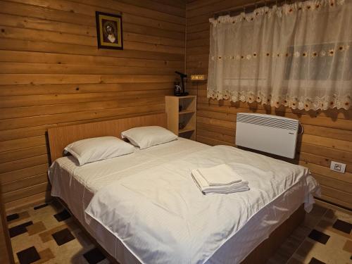 a bedroom with a bed with white sheets and a window at WHITE HOUSE, Vidraru in Căpăţîneni-Pămînteni