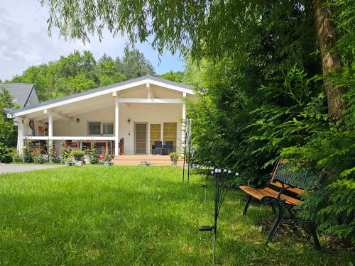 a bench sitting in the grass in front of a house at WHITE HOUSE, Vidraru in Căpăţîneni-Pămînteni