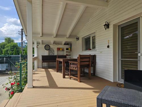 a deck with a table and chairs on a house at WHITE HOUSE, Vidraru in Căpăţîneni-Pămînteni