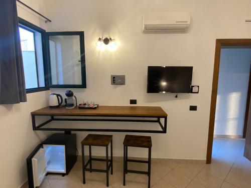 a room with a desk with stools and a tv at affittacamere in centro MUSCI' ROOMS e SUITES in Tortolì