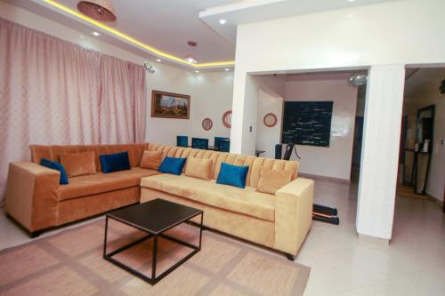 a living room with a couch and a table at Le "Grand Bleu", un bel appartement paisible, sûr et spatieux au cœur de la station balnéaire de Saly Portudal in Saly Portudal