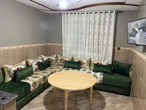 a living room with a green couch and a table at Chez mimoun in Berkawe