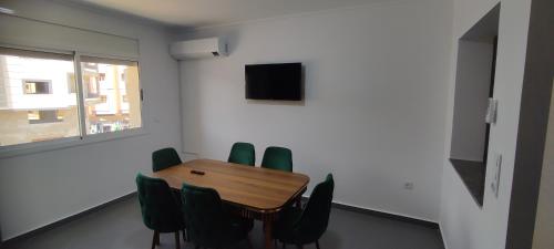 una sala de conferencias con mesa de madera y sillas verdes en Logement familial en Selouane