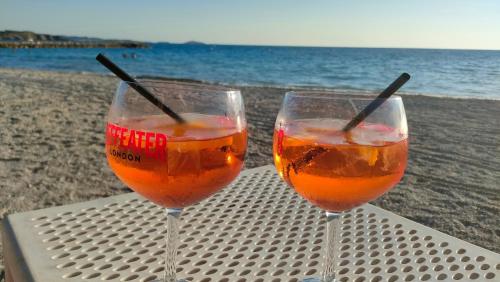 コリウールにあるLa perle de Collioure à 100 métres de la plage de sable fin avec piscine et parkingのビーチのテーブルに座ったワイングラス2杯