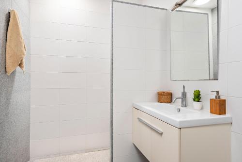 Un baño blanco con lavabo y espejo. en Villa Cau Ventos, en Cala Galdana