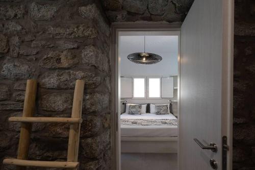 a bedroom with a bed in a room with a stone wall at OLIVES seaside villas villa no 2 in Plaka