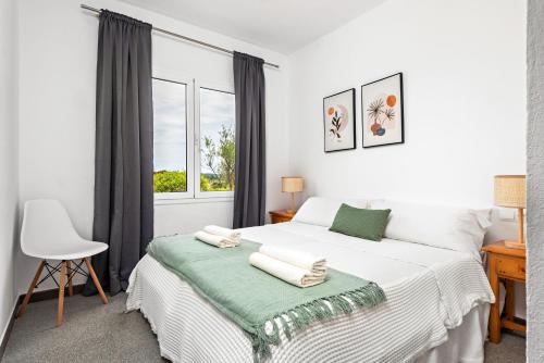 Una habitación blanca con una cama y una ventana en Villa Cau Ventos, en Cala Galdana