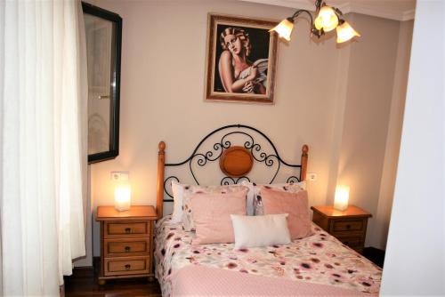 - une chambre avec un lit avec des oreillers roses et 2 lampes dans l'établissement El Fuste, à Oviedo