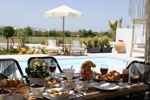 una mesa con comida y vino junto a una piscina en OLIVES seaside villas (4elies), en Plaka
