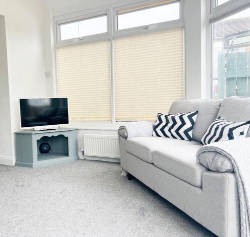 een woonkamer met een bank en een flatscreen-tv bij Field House in Boroughbridge